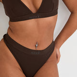 Pair your bralet with our matching Cotton Lyocel Ribbed Thong for a complete look of effortless elegance. The thong offers minimal coverage with maximum comfort, featuring the same soft and breathable fabric blend. The ribbed texture and sleek design ensure a smooth fit under any garment, while the elastic waistband with our signature logo provides a secure yet gentle hold.